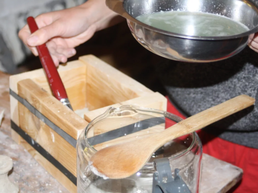 Un moule en bois avec une personne versant du plâtre liquide dans un récipient en métal.