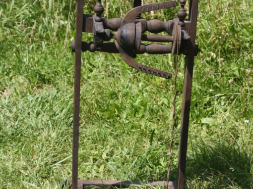 Rouet vertical en métal avec des détails en bois, utilisé pour le filage de la laine.
