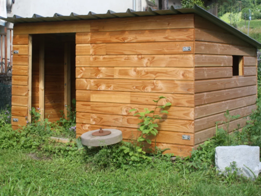 Cabane en bois avec un toit en métal, construite avec des planches de bois brun clair.